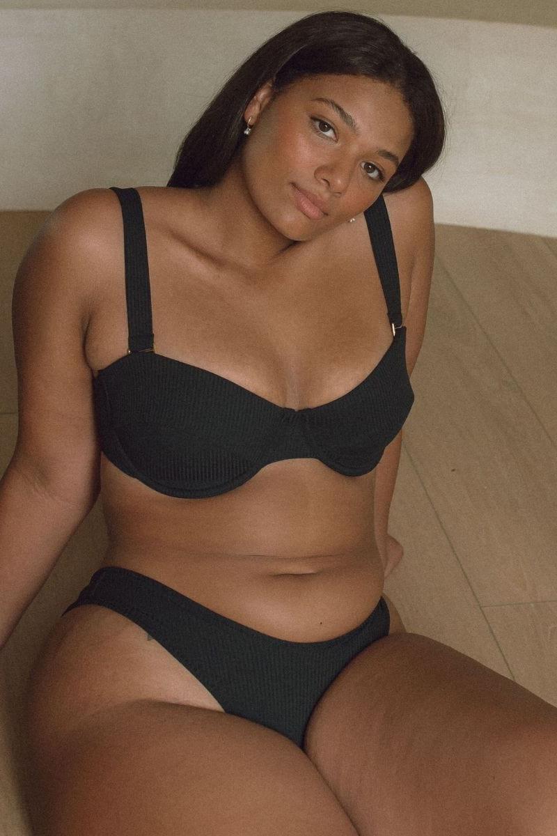 Black ribbed bikini top with underwire cups and adjustable shoulder straps on model.