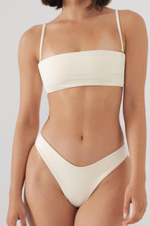 Cream ribbed bikini bottom with high-cut leg and thin side straps on model.
