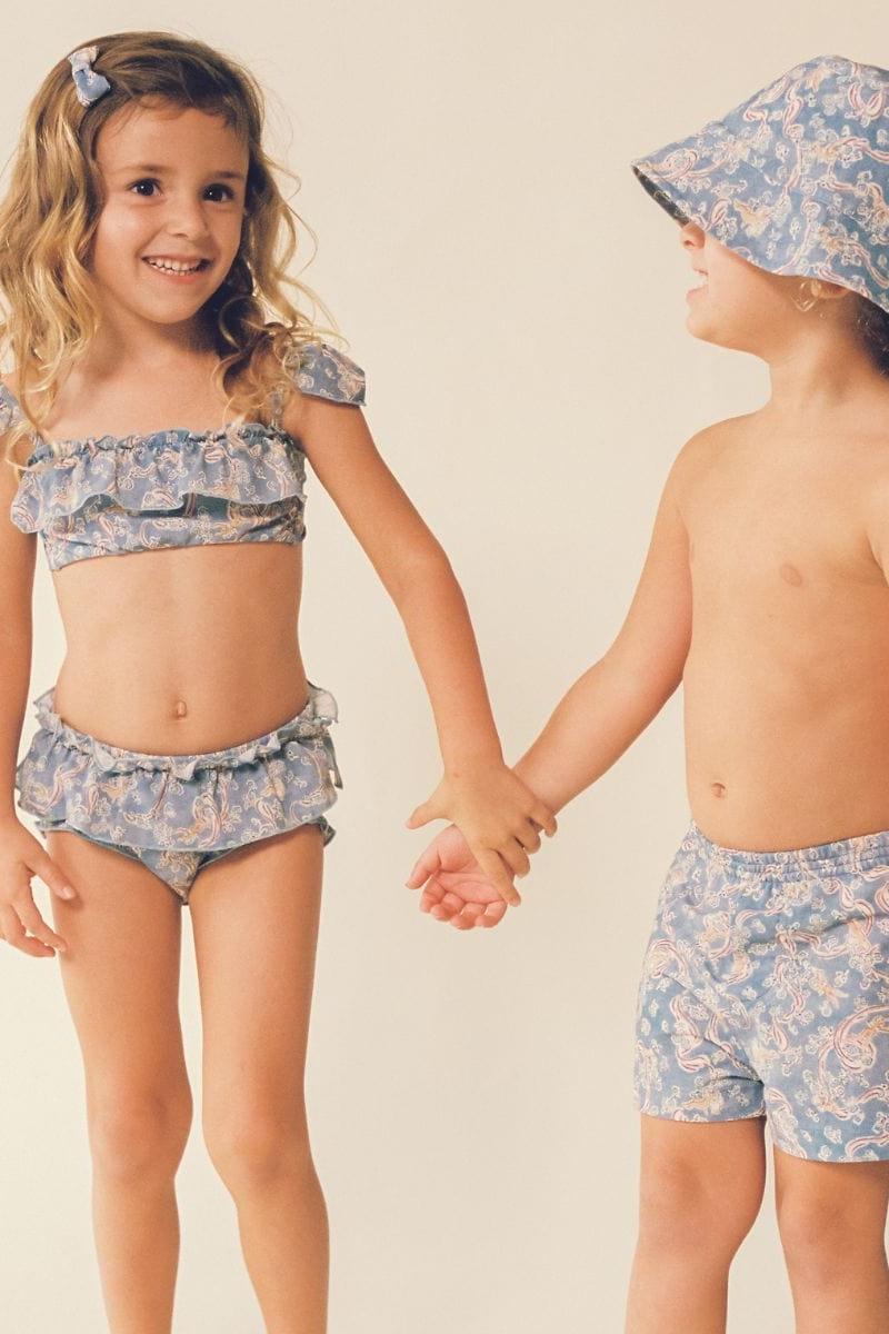 Child wearing blue paisley bucket hat and matching swimwear, shown from front and side angles.
