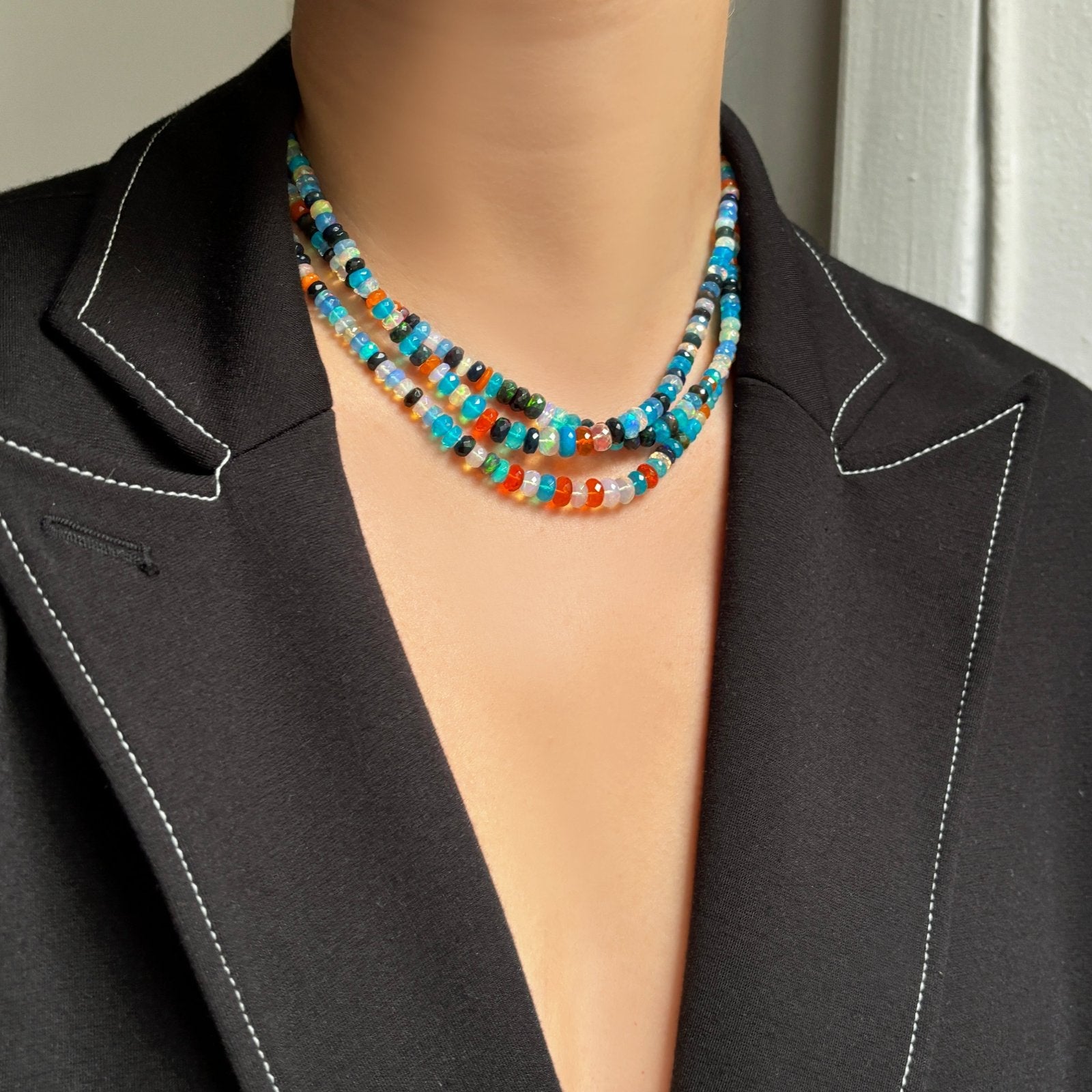 A model wears a blazer and a triple strand of Jaipur Jazz faceted opal necklaces around her neck.