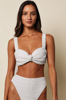 White textured bikini top with bow detail and square neckline on model.