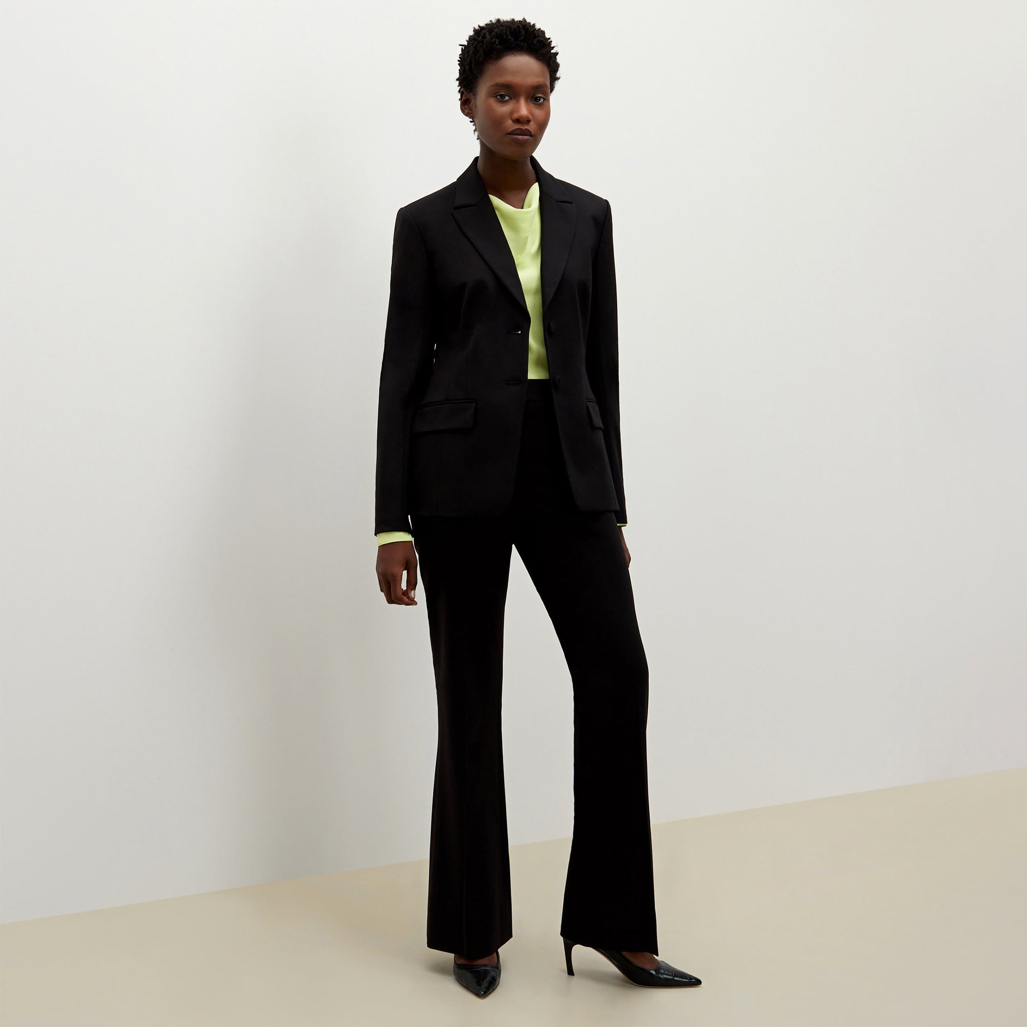Front image of a woman standing wearing the bennett blazer wool twill in black | Exclude