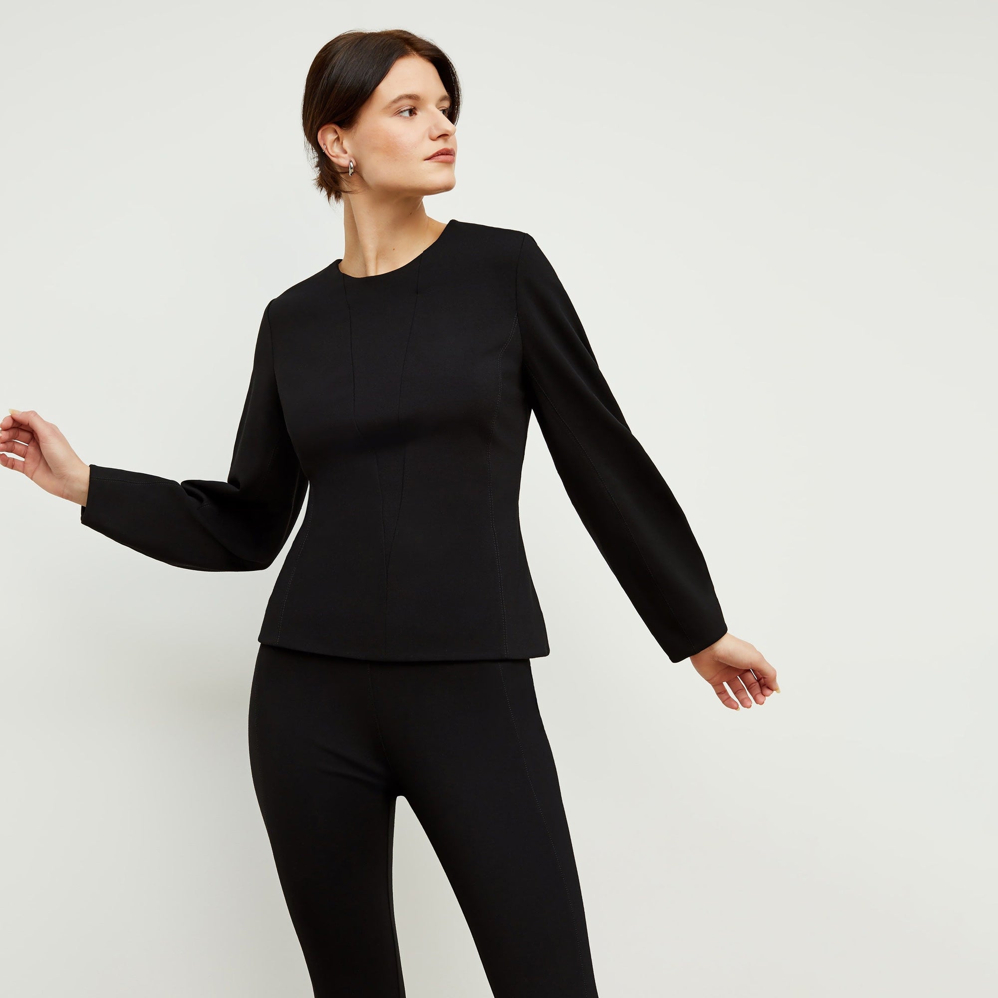 Front image of a woman standing wearing the rashida top in black