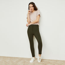 Front image of a woman standing wearing the curie pant in dark olive | Exclude