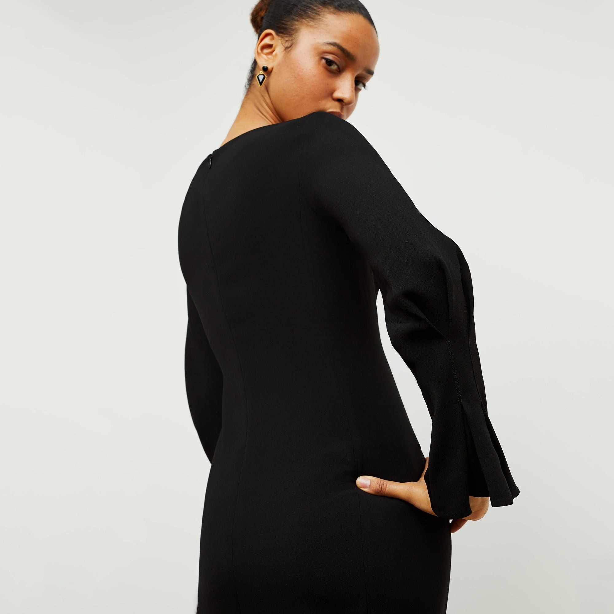 Back image of a woman standing wearing the Regina Dress in Black