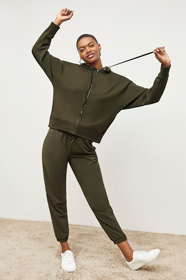Front image of a woman standing wearing the Delaney Jogger—OrigamiTech in Olive | Grid | Exclude