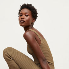 Side image of a woman standing wearing the Finley Legging—Ribbed Jardigan Knit in Light Bronze | Exclude