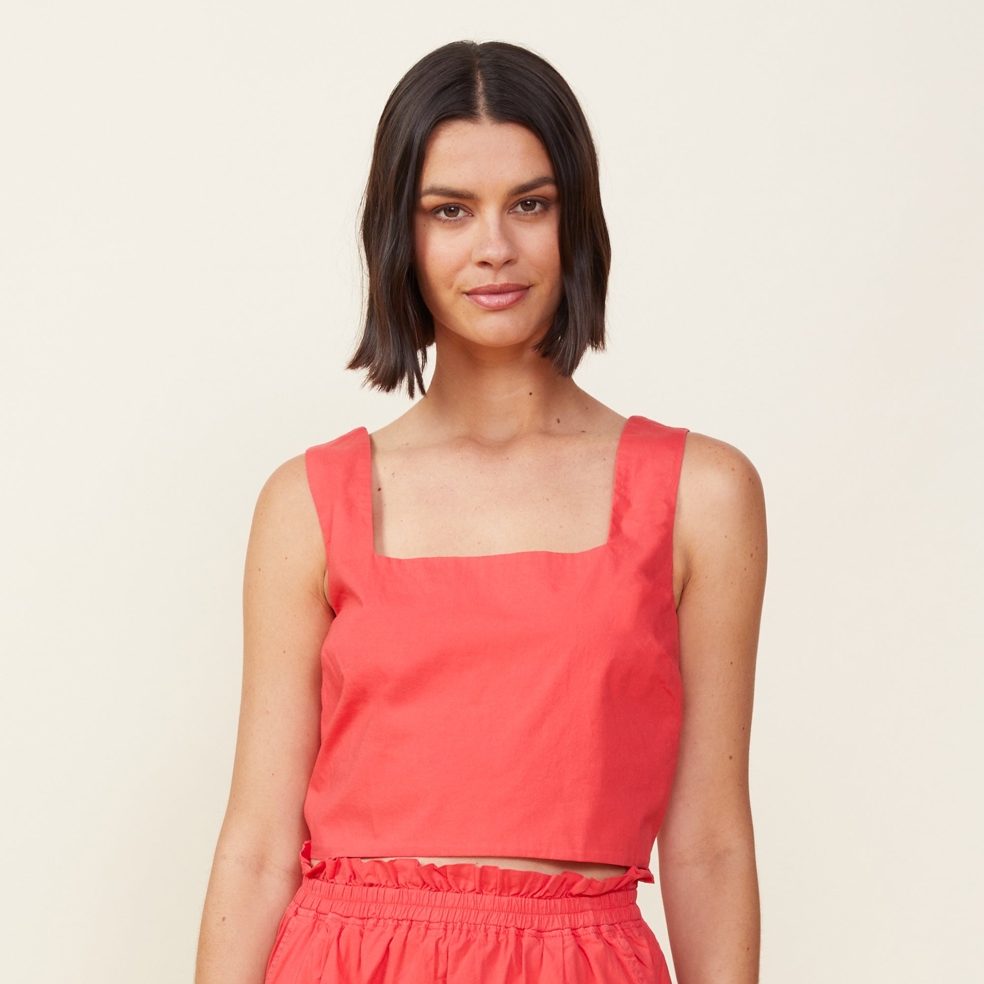 Front view of model wearing the poplin tank in fire coral.