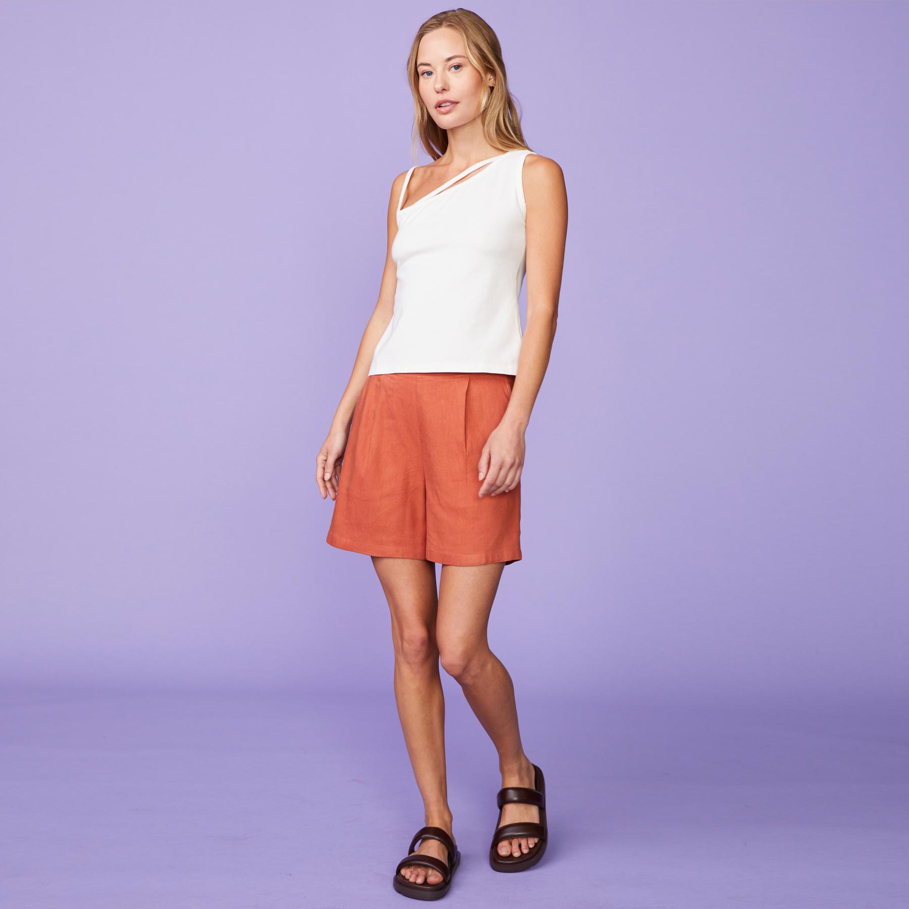 Front view of model wearing the linen pleated shorts in faded rust.