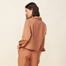 Back view of model wearing the cropped poplin shirt in sahara.