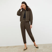 Back image of a woman standing wearing the Delaney Jogger—OrigamiTech in Olive | Lead