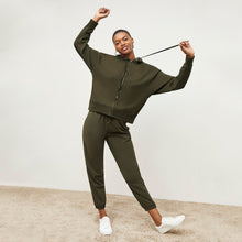Front image of a woman standing wearing the Delaney Jogger—OrigamiTech in Olive
