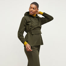 Side image of a woman standing wearing the Delaney Jogger—OrigamiTech in Olive | Exclude