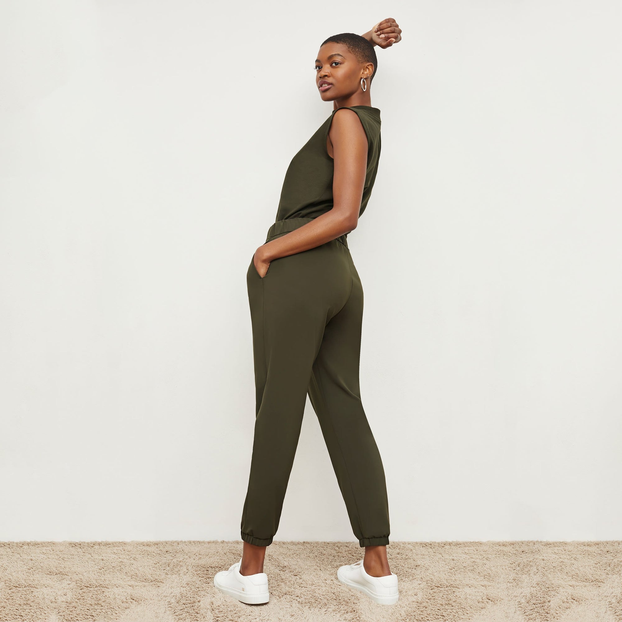 Back image of a woman standing wearing the Delaney Jogger—OrigamiTech in Olive